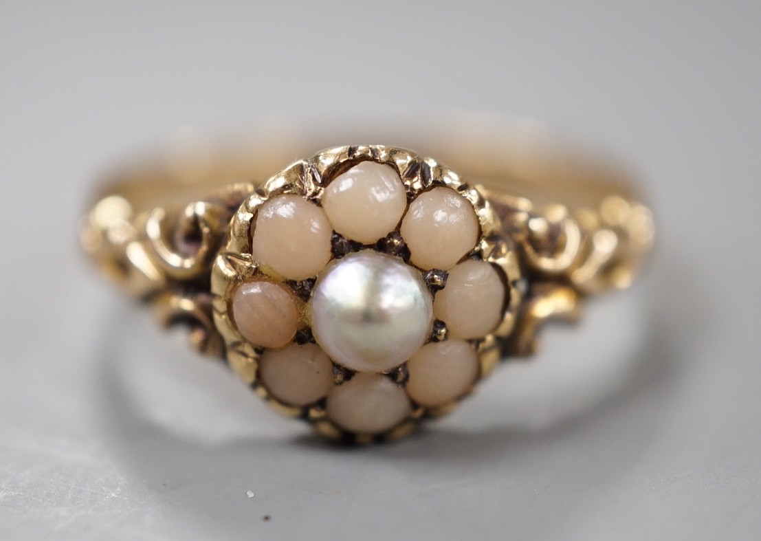 An early 20th century yellow metal, split coral and split pearl cluster set ring, size P, gross weight 2.5 grams.